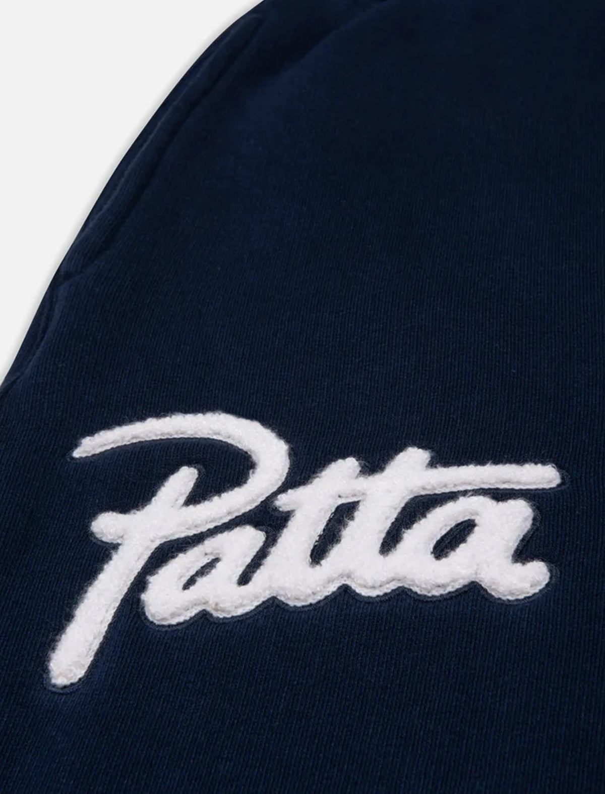 Close-up of a navy blue garment with 'Patta' logo in white.