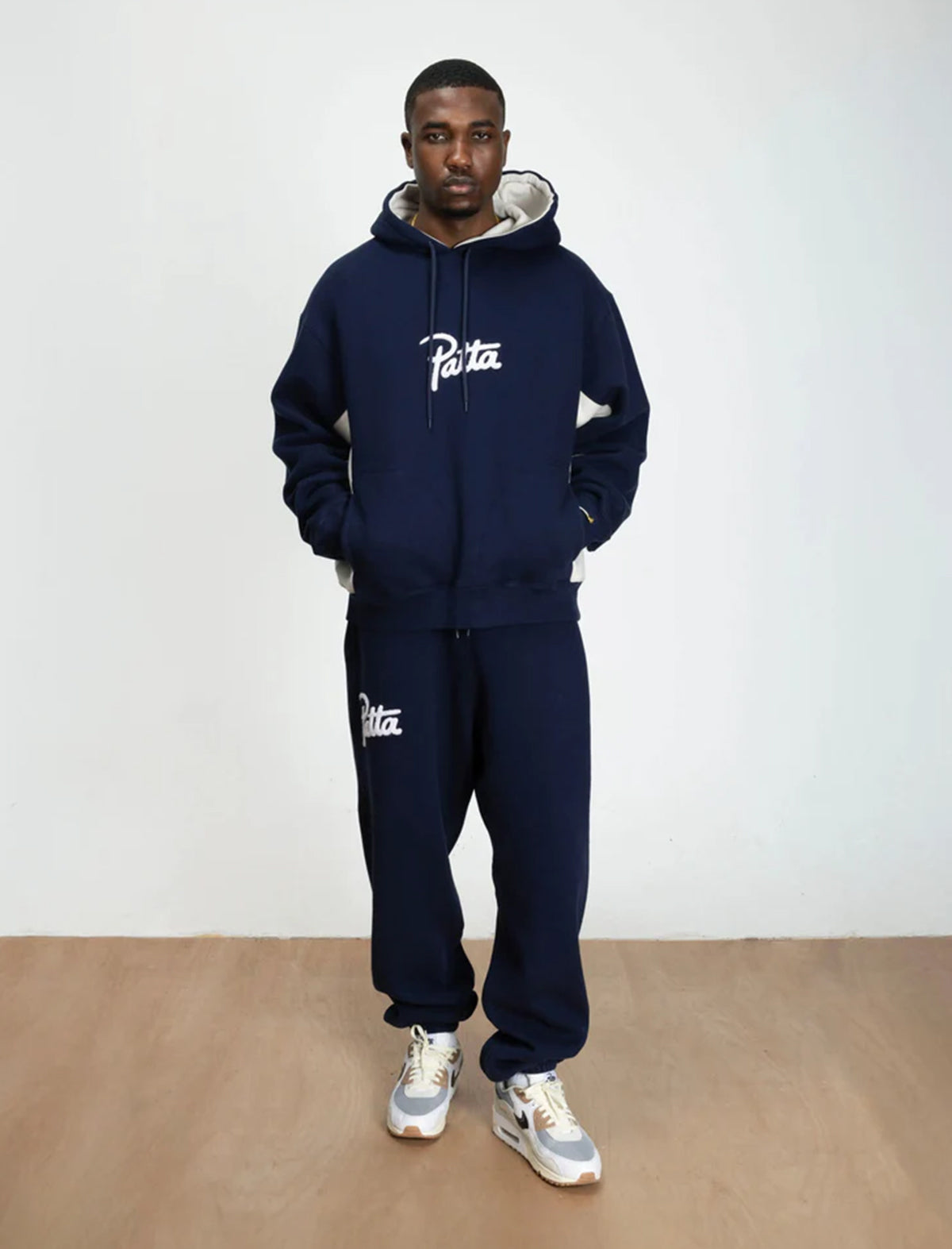 Person wearing a navy tracksuit with 'Patta' branding against a white background