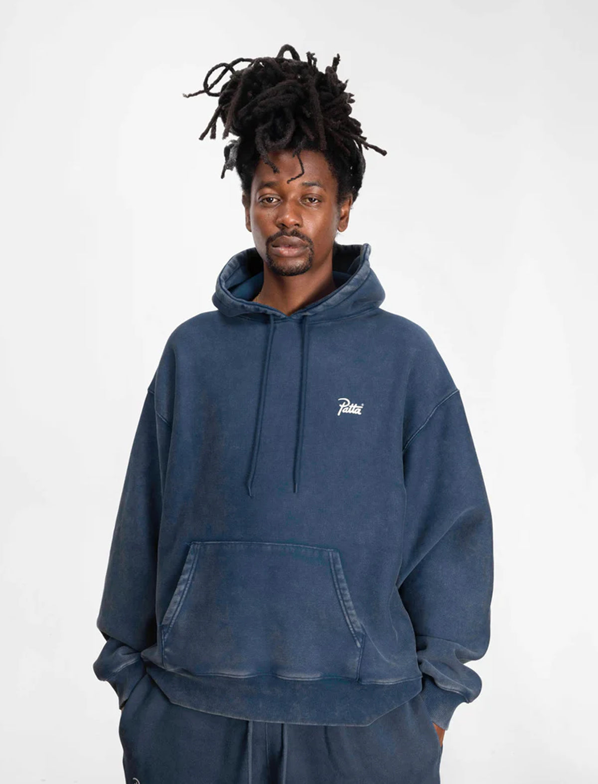Man wearing a Patta blue hoodie with a small logo on a white background