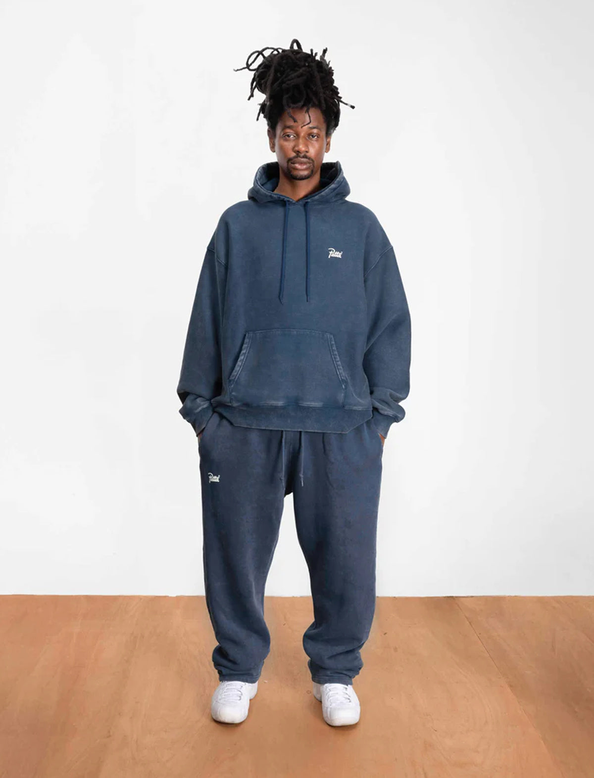 Person wearing a Patta blue hoodie and sweatpants set on a white background