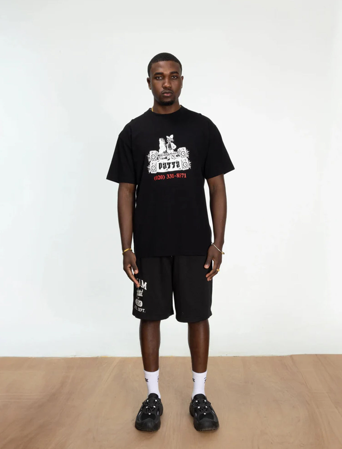Person wearing a patta black t-shirt and shorts with a graphic design on a white background