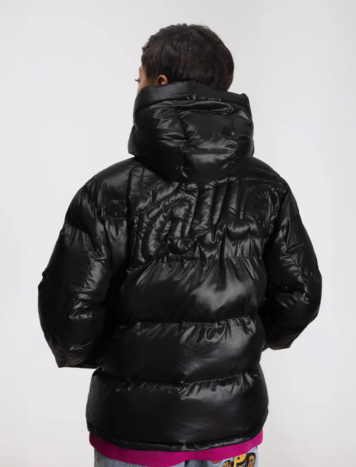 Person wearing a black Patta puffer jacket on a white background