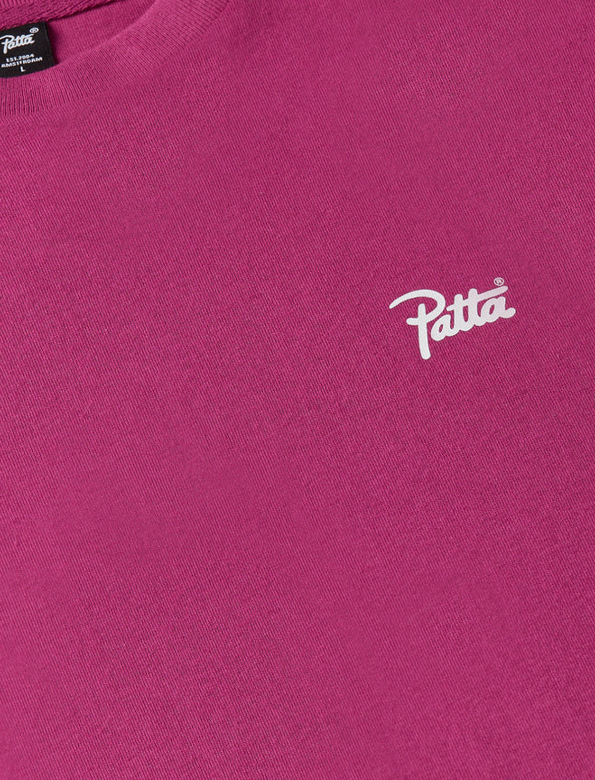 Close-up of a pink t-shirt with a white Patta logo on a pink background