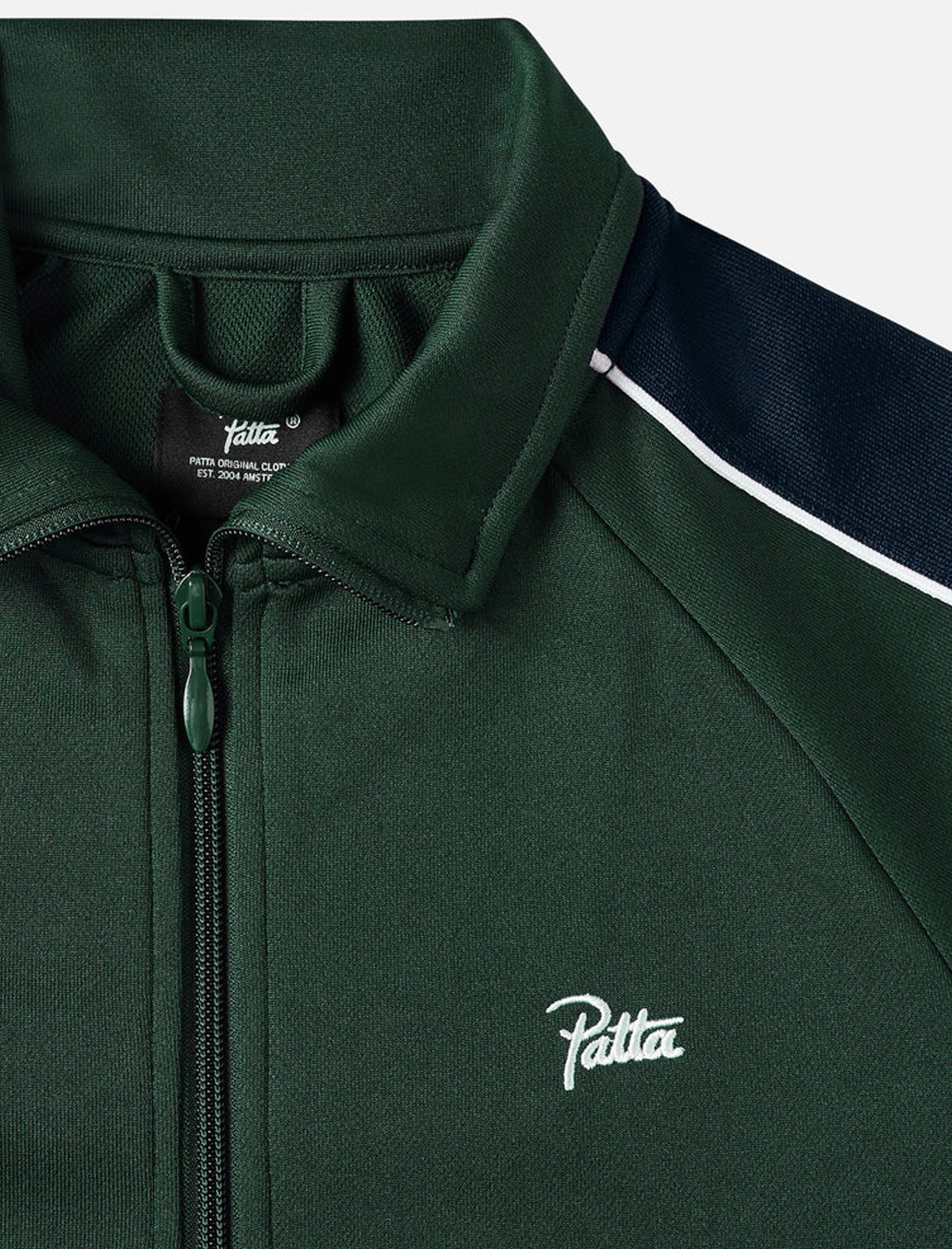 Close-up of a green jacket with 'Patta' branding on a white background