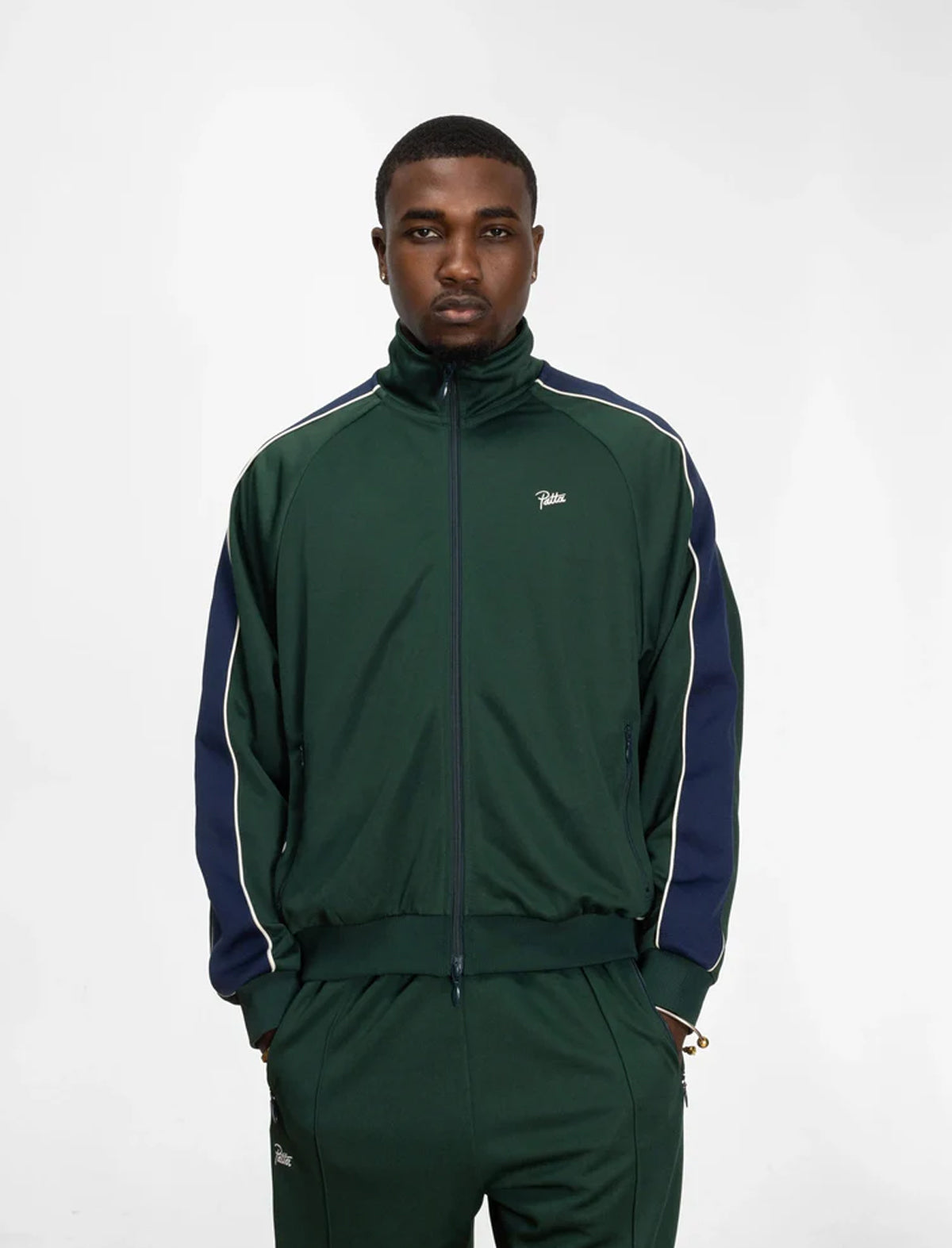 Man wearing a green tracksuit with white stripes on a white background