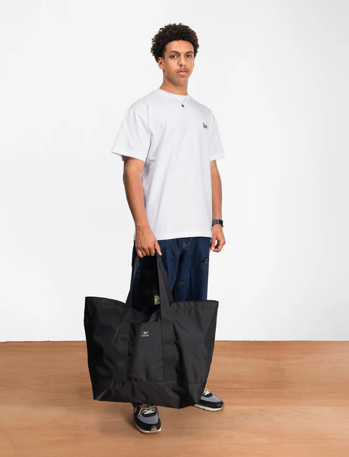 Man holding a black Patta bag against a white background