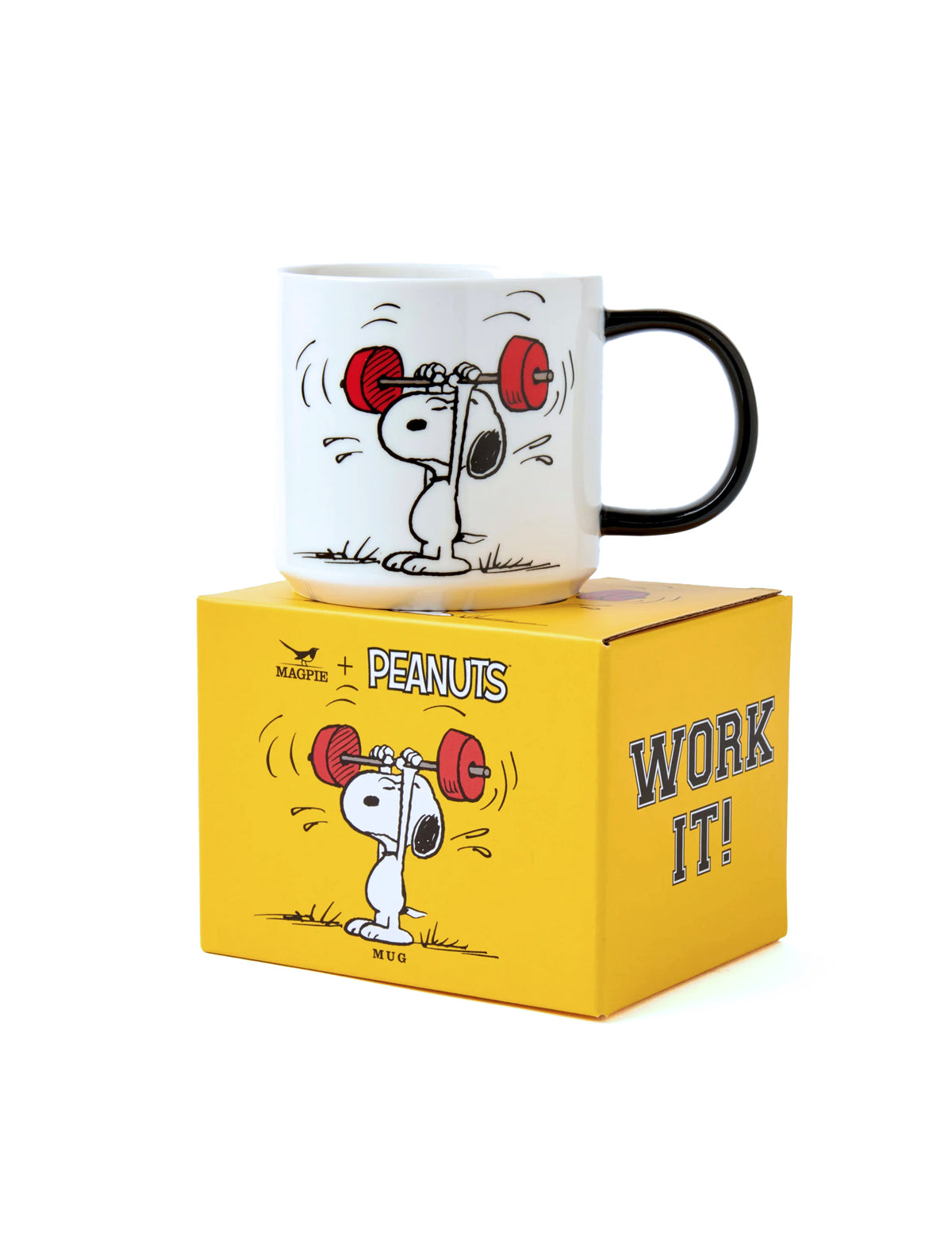 A white ceramic mug with a black handle and Snoopy lifting red weights, displayed on top of a yellow Peanuts box that reads 'WORK IT!'.