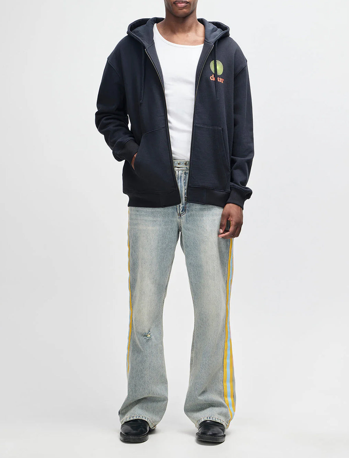 Person wearing a dark hoodie, white t-shirt, and light gray jeans with yellow stripes on a white background