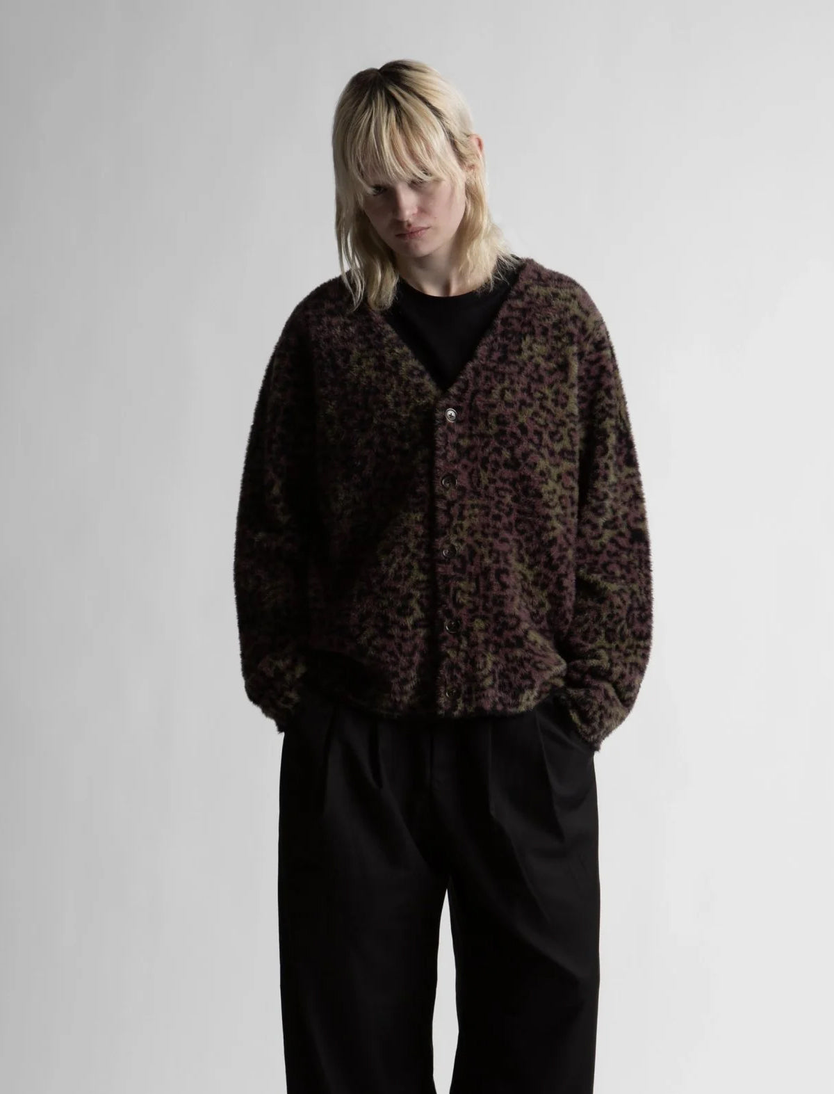 Person wearing a leopard print jacket and black pants on a plain background