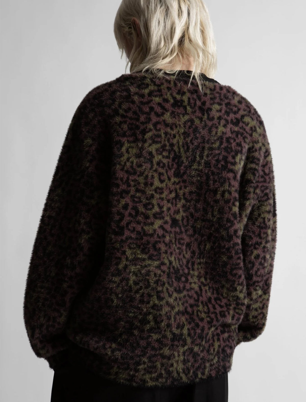 Person wearing a leopard print sweater against a plain background