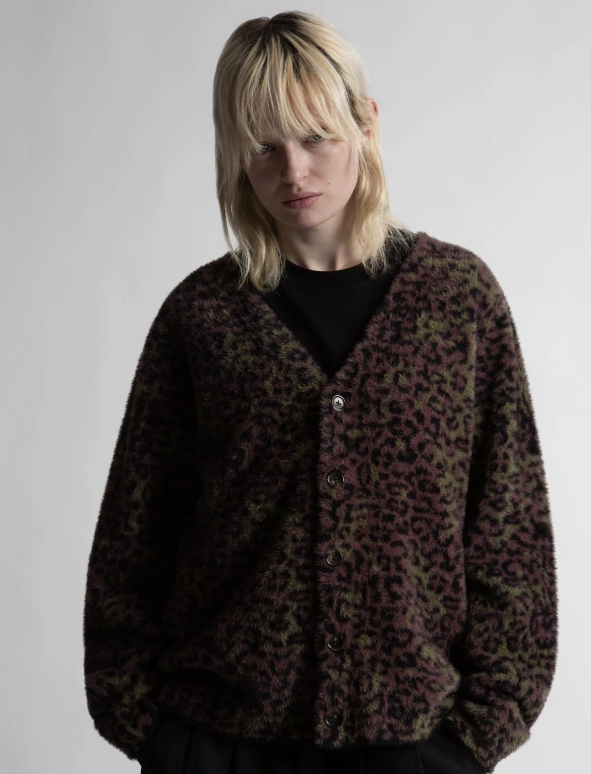 Person wearing a leopard print cardigan on a plain background
