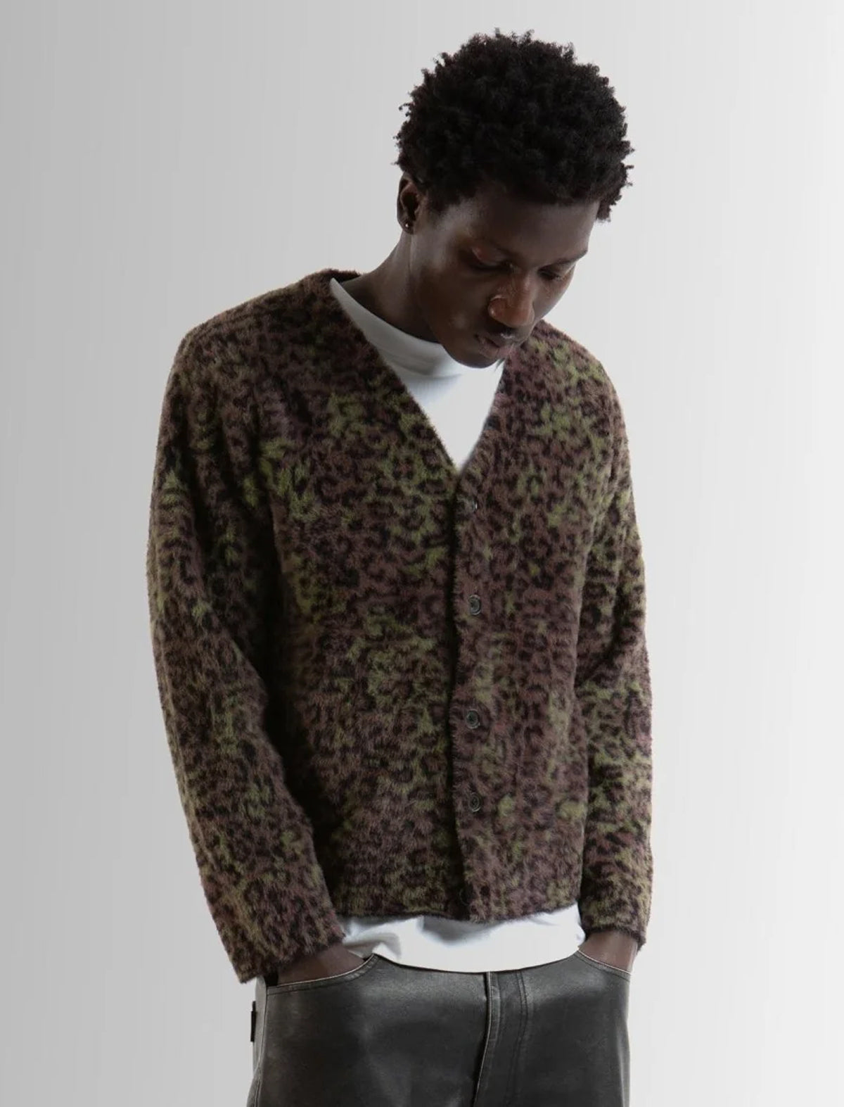 Person wearing a leopard print cardigan over a white shirt on a plain background