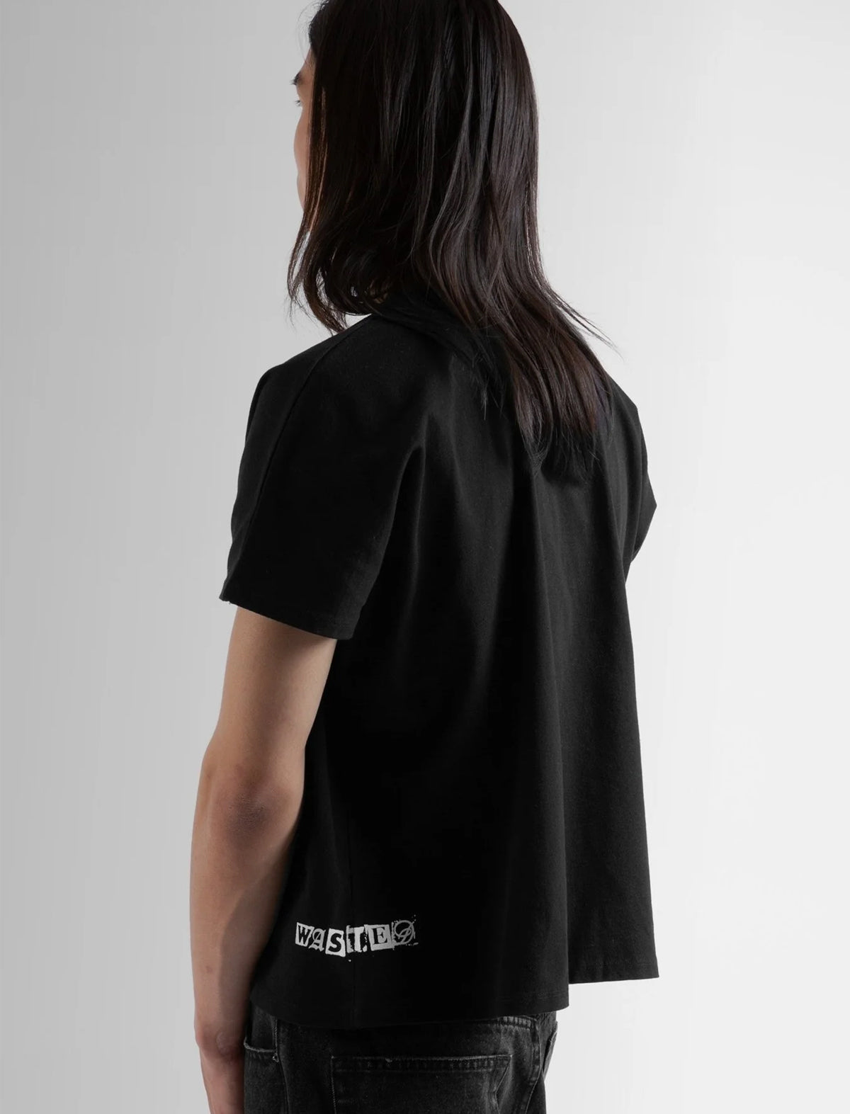 Person wearing a black t-shirt with a logo on the back against a white background