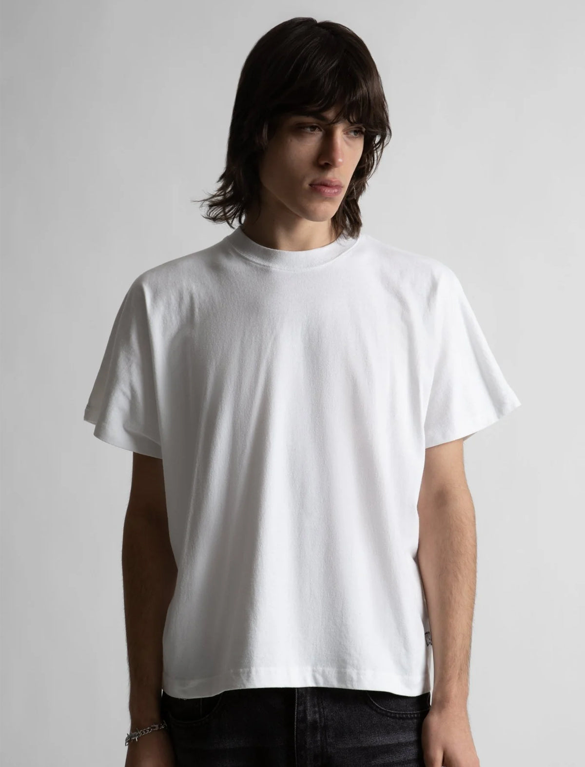 Person wearing a plain white t-shirt against a light gray background