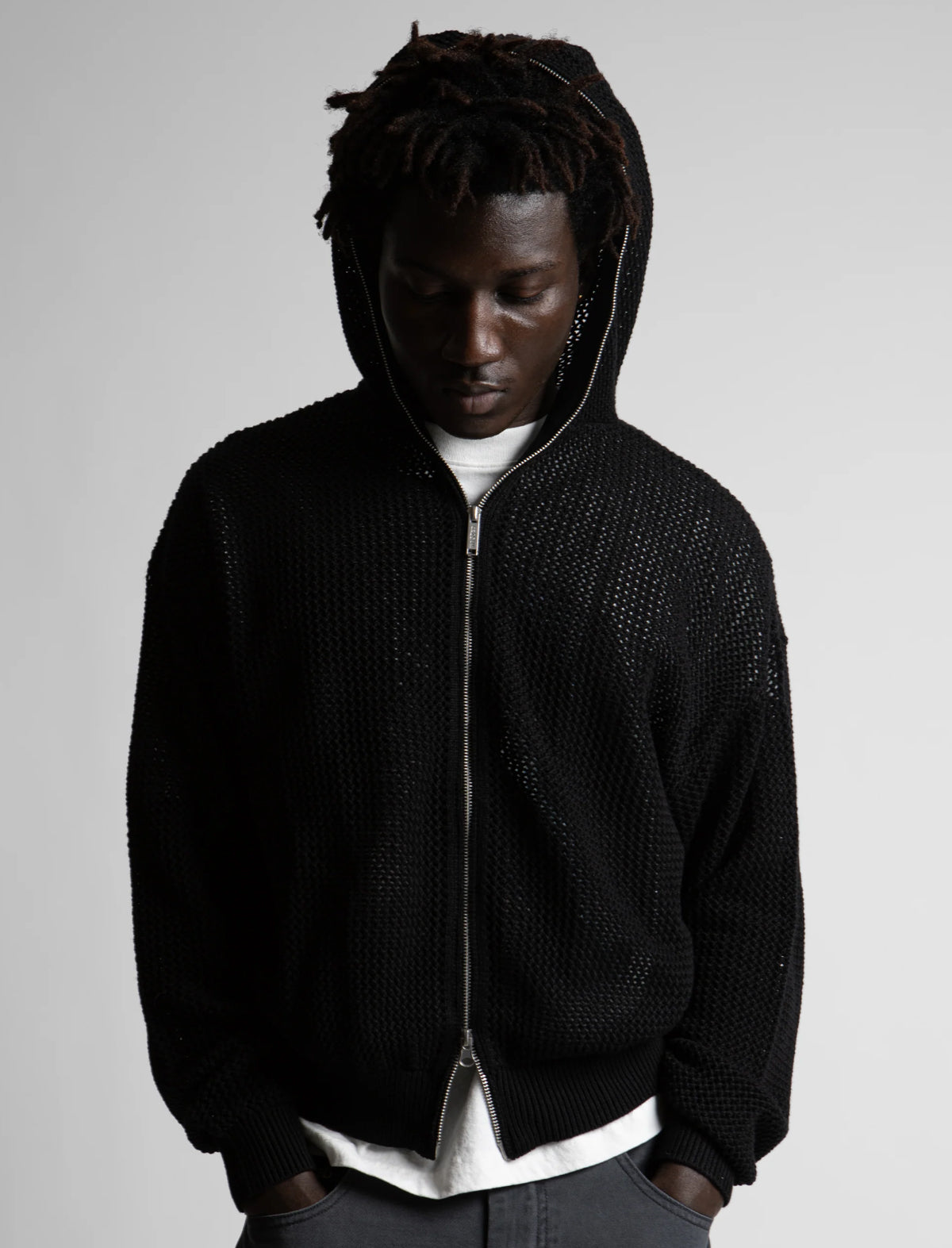 Person wearing a black textured hoodie against a plain background