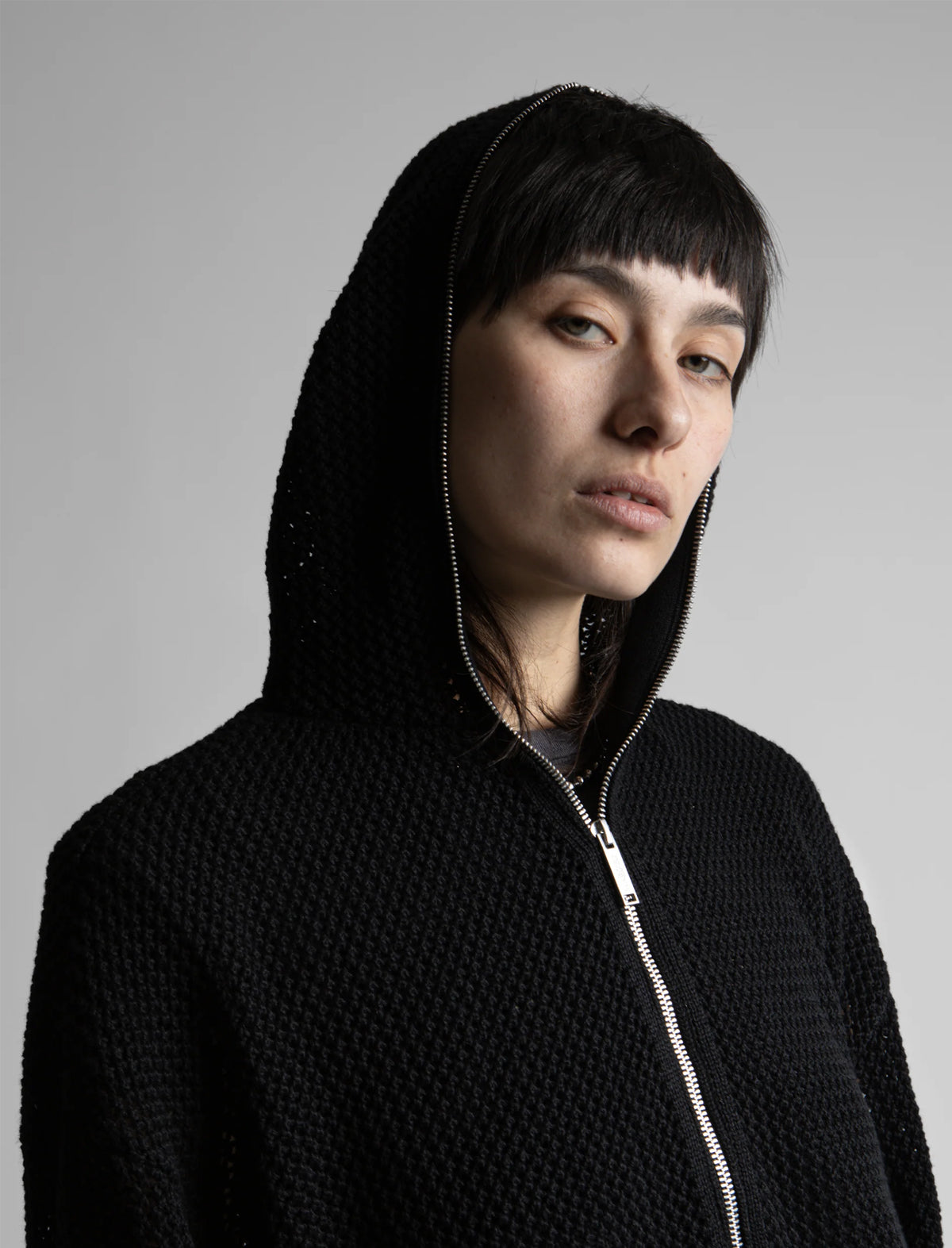 Person wearing a black hoodie against a gray background