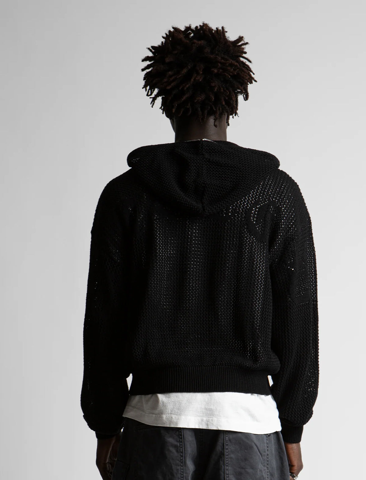 Person wearing a black textured hoodie with a plain background