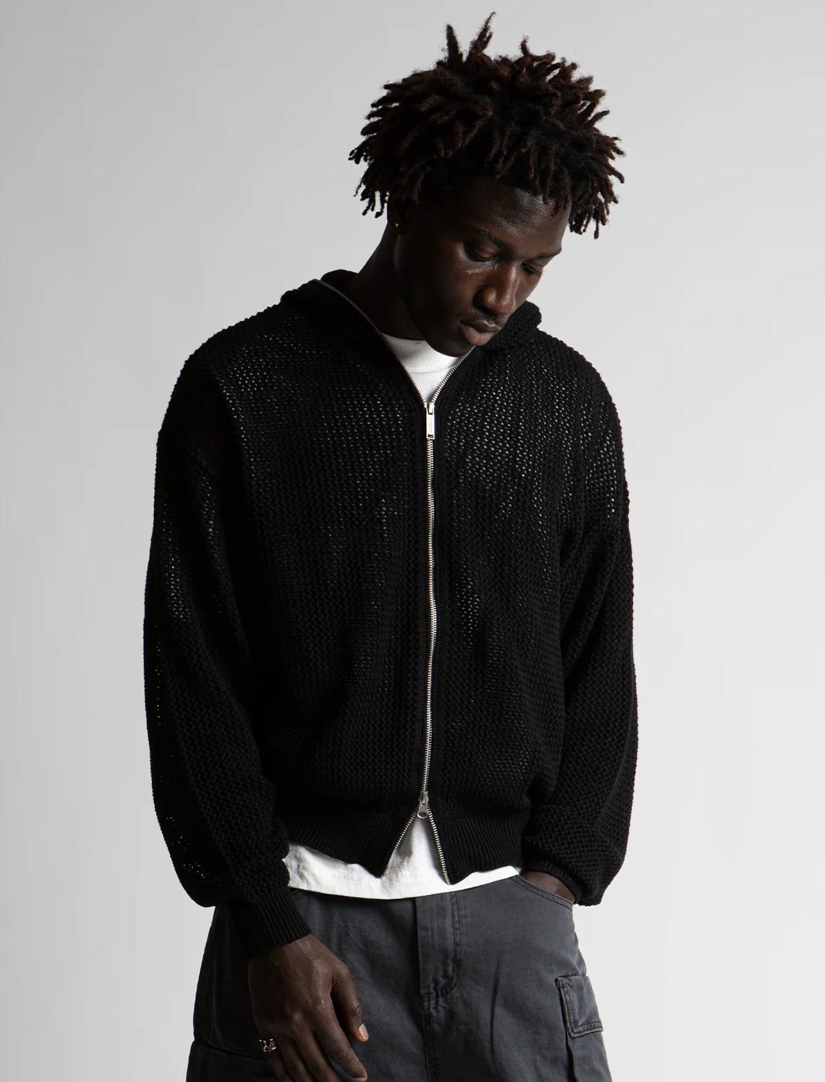 Man wearing a black textured zip-up hoodie on a plain background