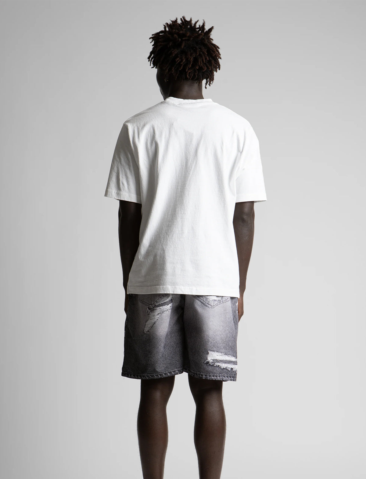 Person wearing a white t-shirt and gray shorts on a plain background