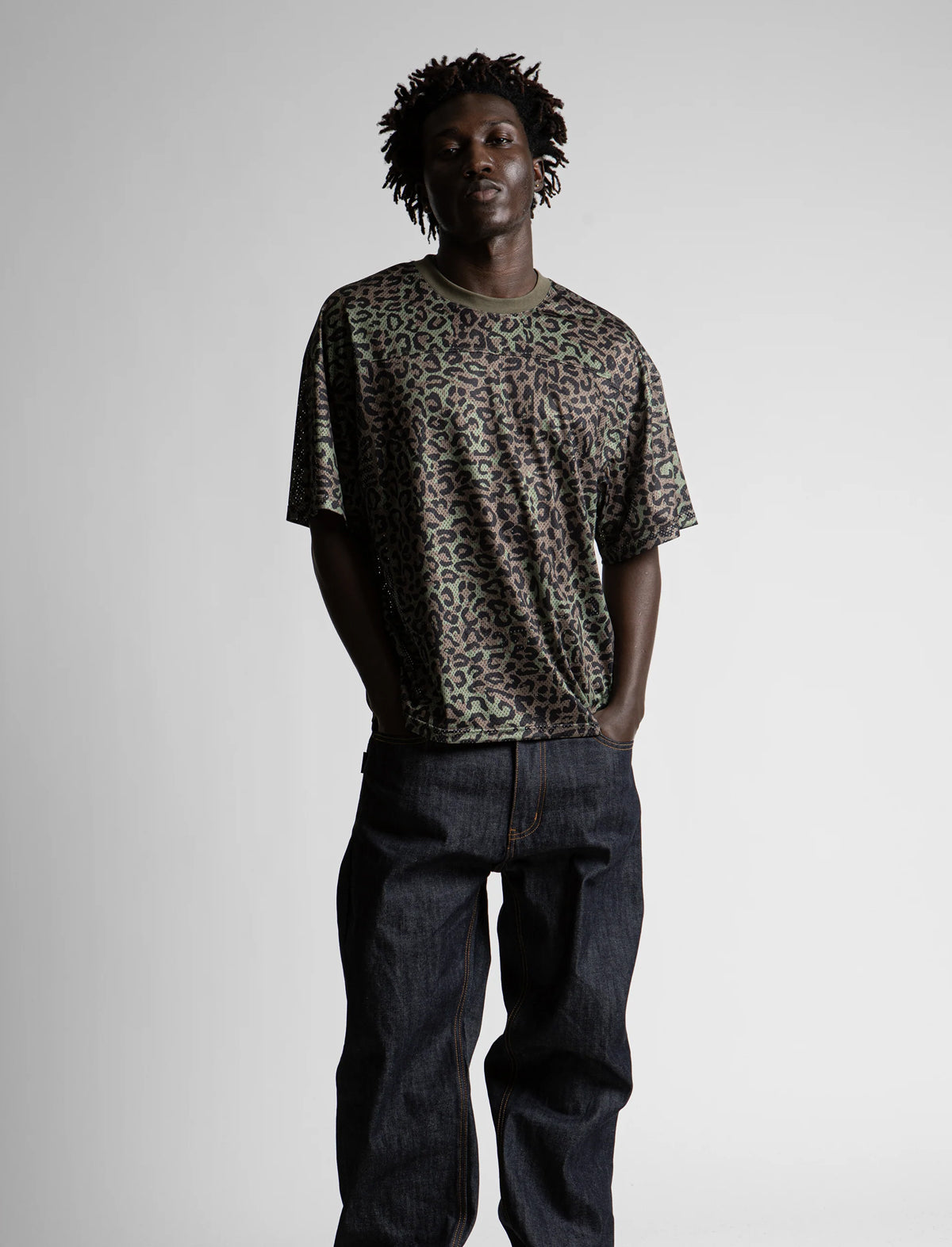 Person wearing a leopard print t-shirt and dark jeans on a plain background