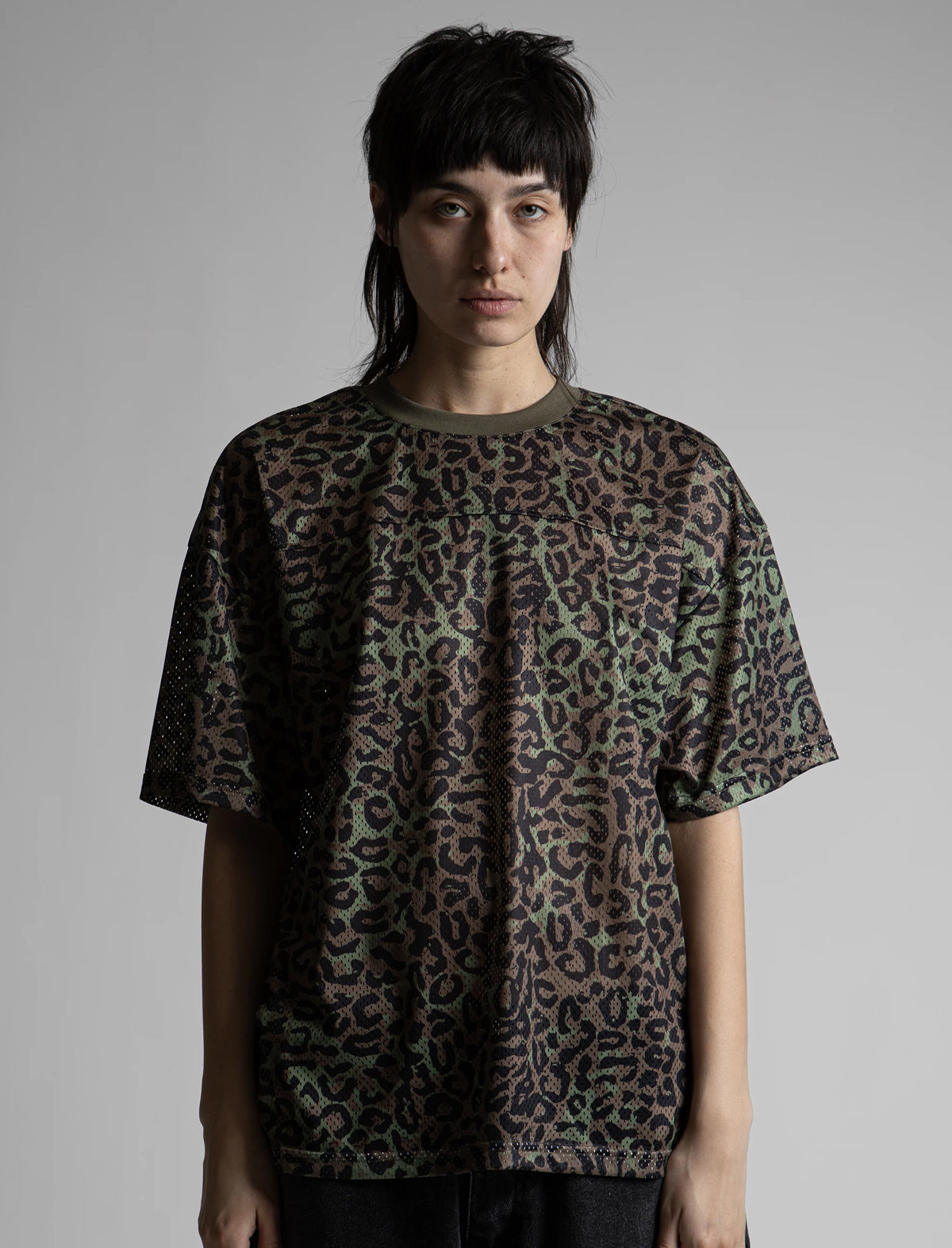 Person wearing a leopard print t-shirt against a plain background