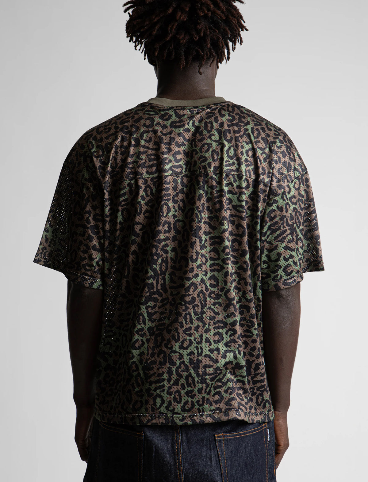 Person wearing a leopard print t-shirt on a plain background