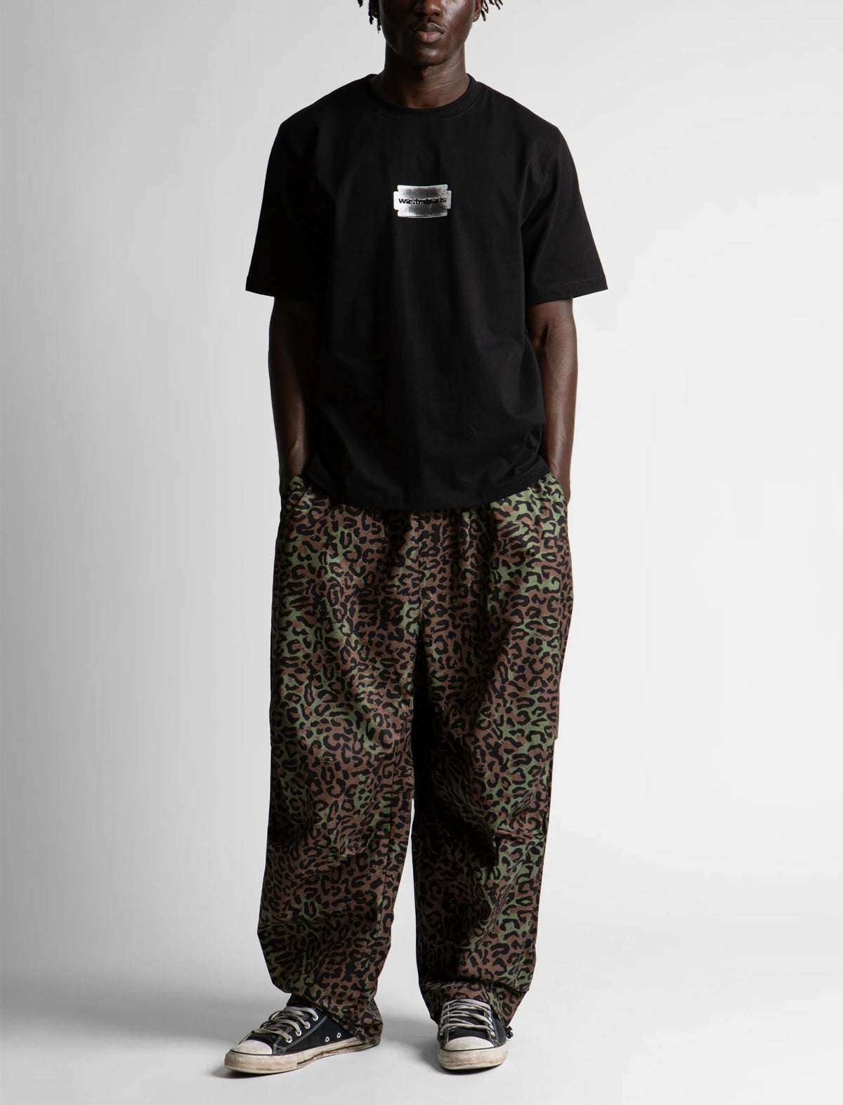 Person wearing a black t-shirt and leopard print pants on a white background