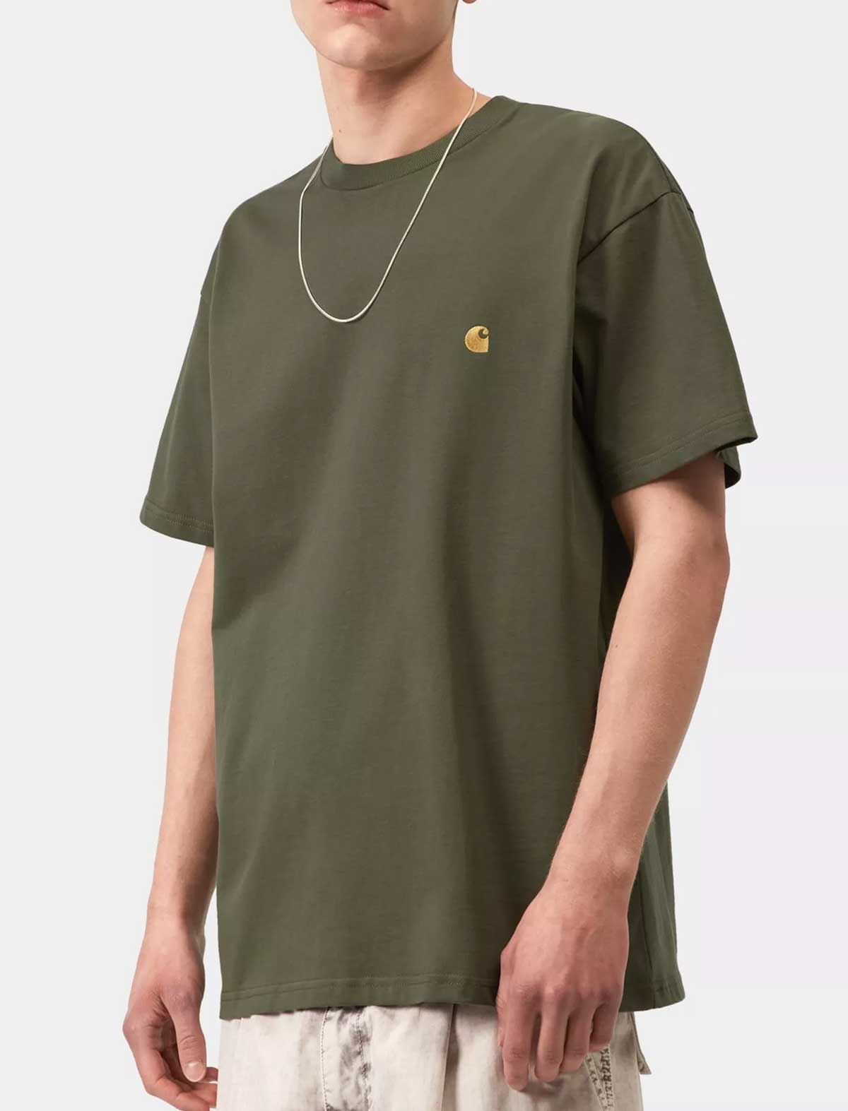 Person wearing a green t-shirt with a small logo on a white background