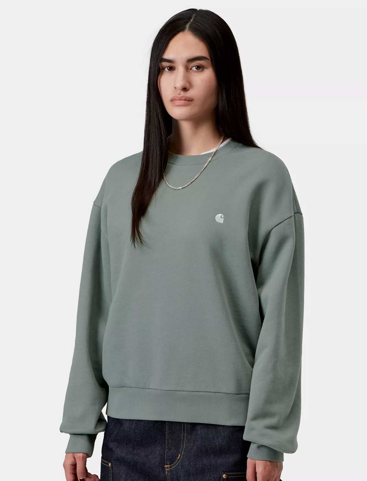 Person wearing a light green sweatshirt with a brand logo on a white background
