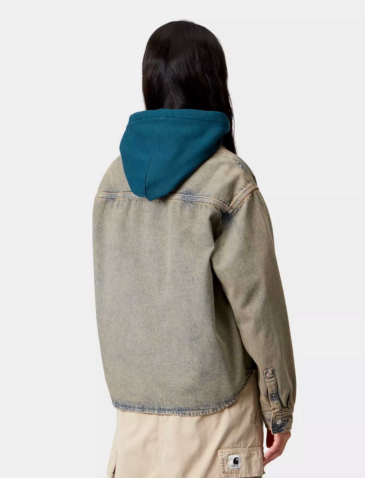 Person wearing a beige denim jacket with a teal hood on a white background
