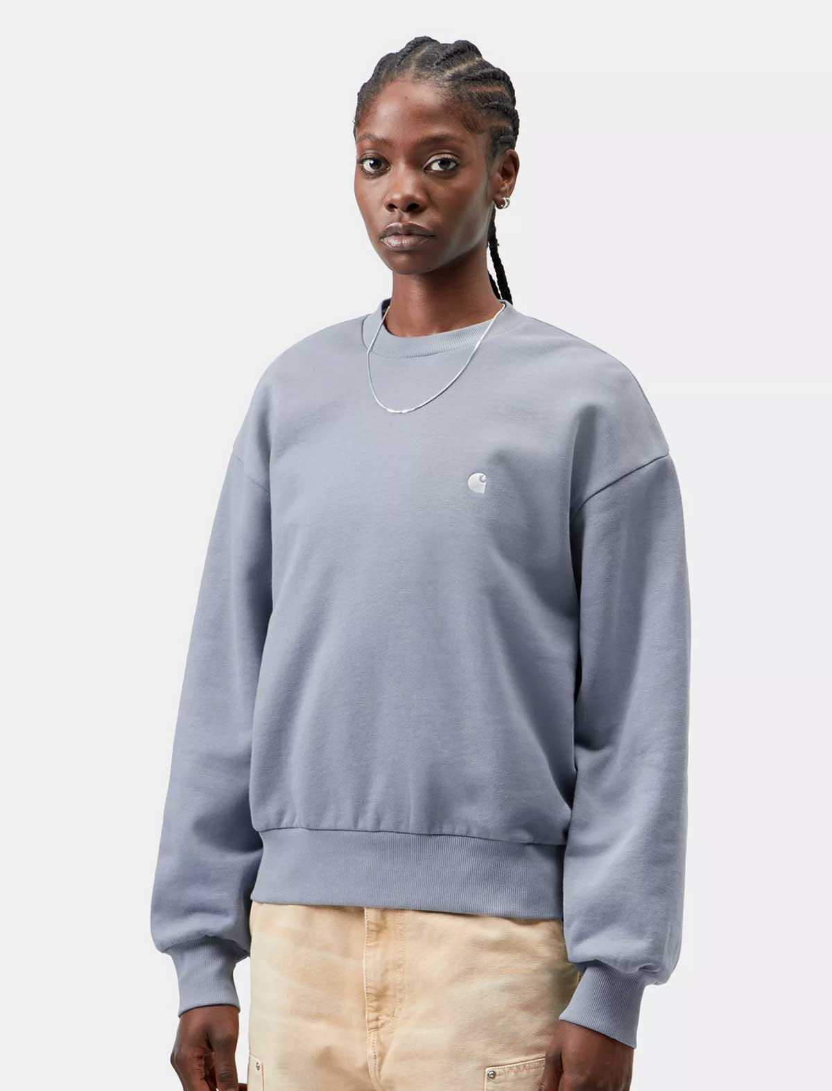 Person wearing a carhartt casey sweatshirt with a small logo on a light gray background