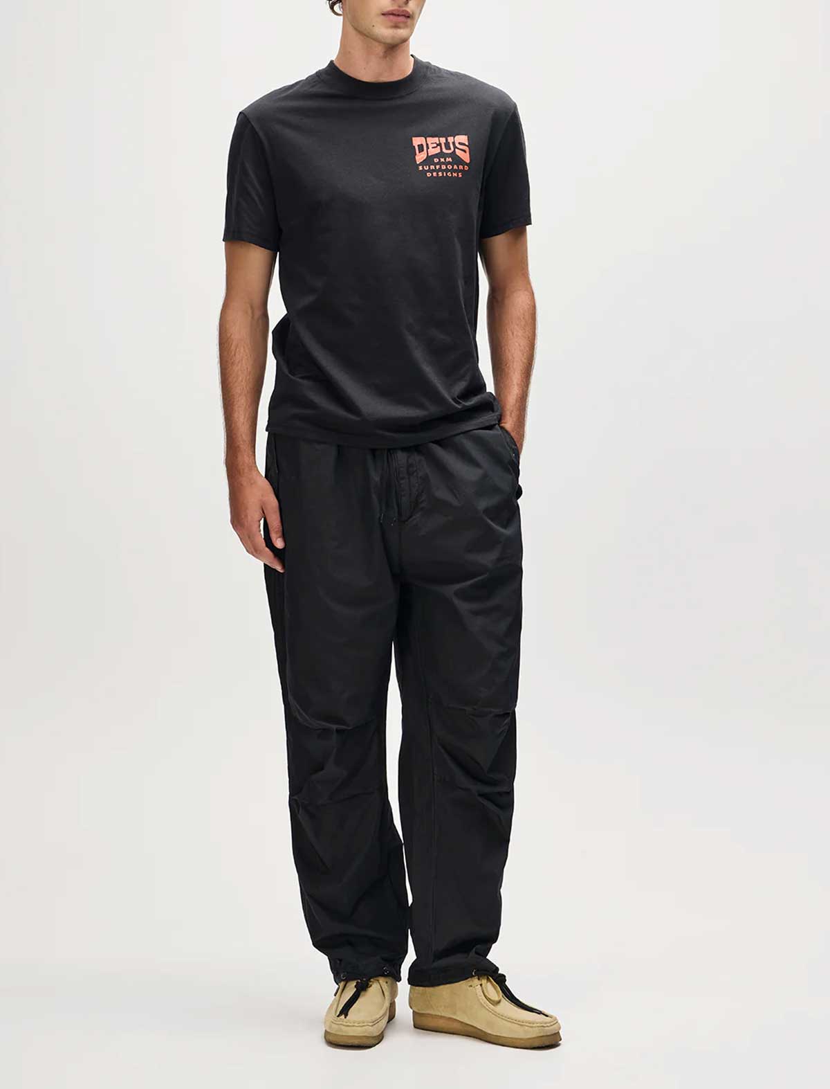 Person wearing a black t-shirt and pants with a brand logo on a white background