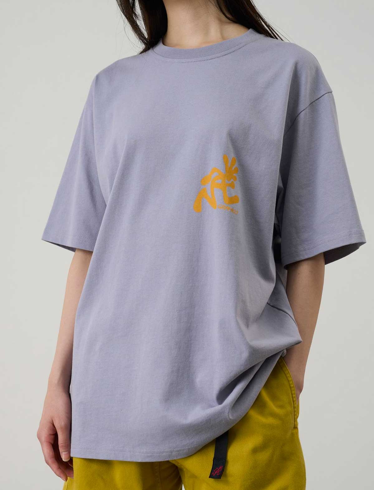 Person wearing a Gramicci light purple t-shirt with yellow text on a plain background