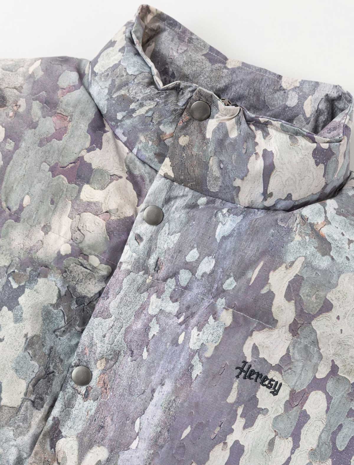 Camouflage jacket with 'Heresy' branding on a white background