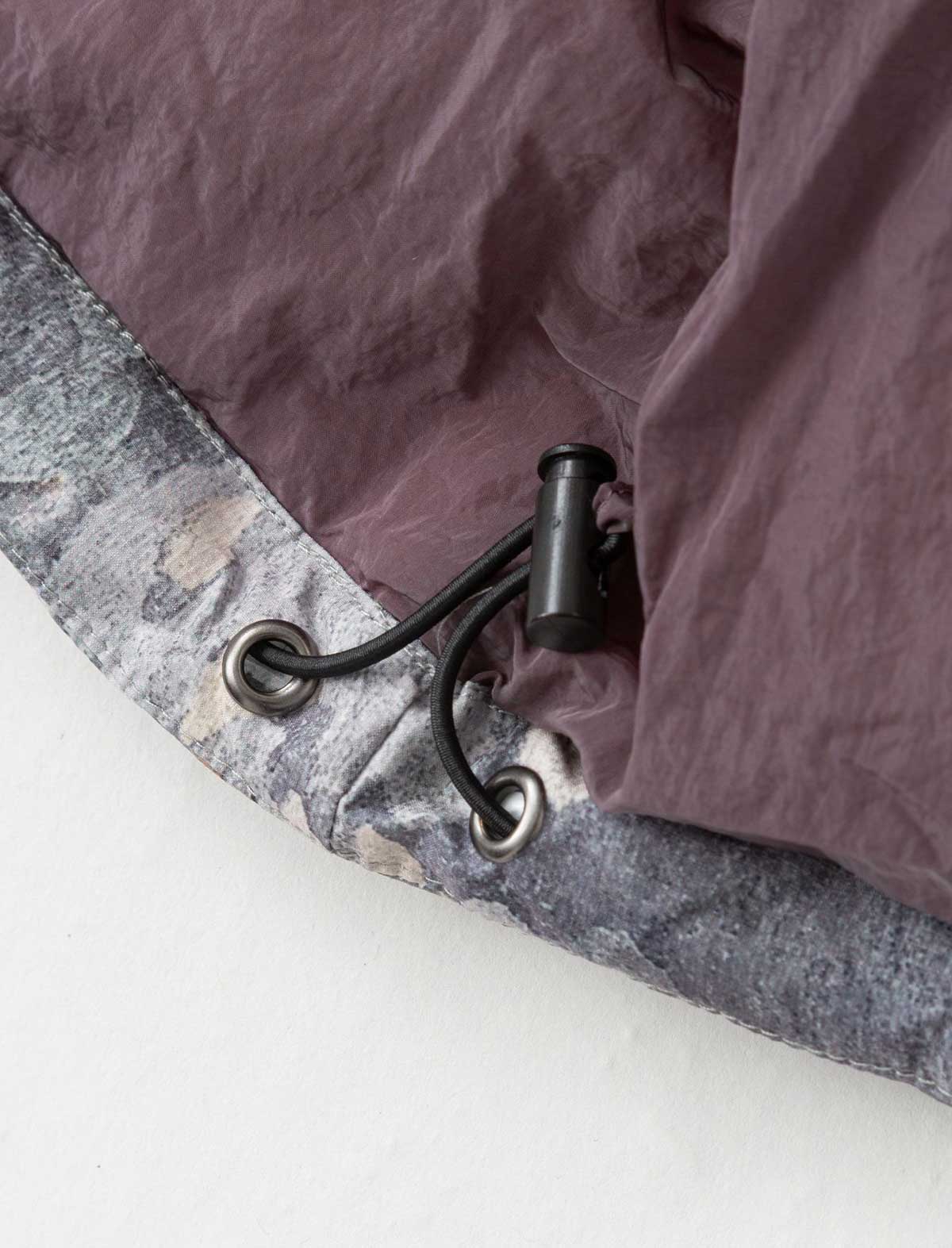 Close-up of a decorative metal hook on a textured surface with a purple fabric background.