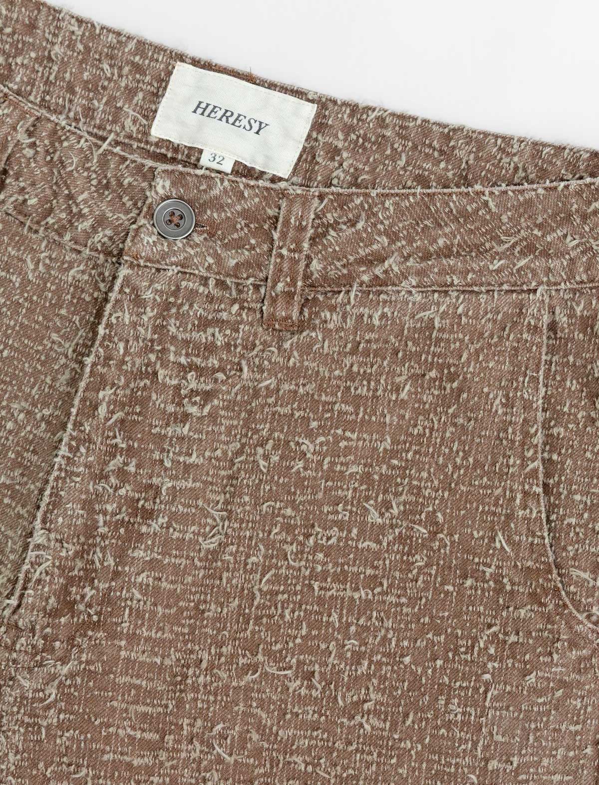 Close-up of brown textured fabric with a 'HERESY' label.