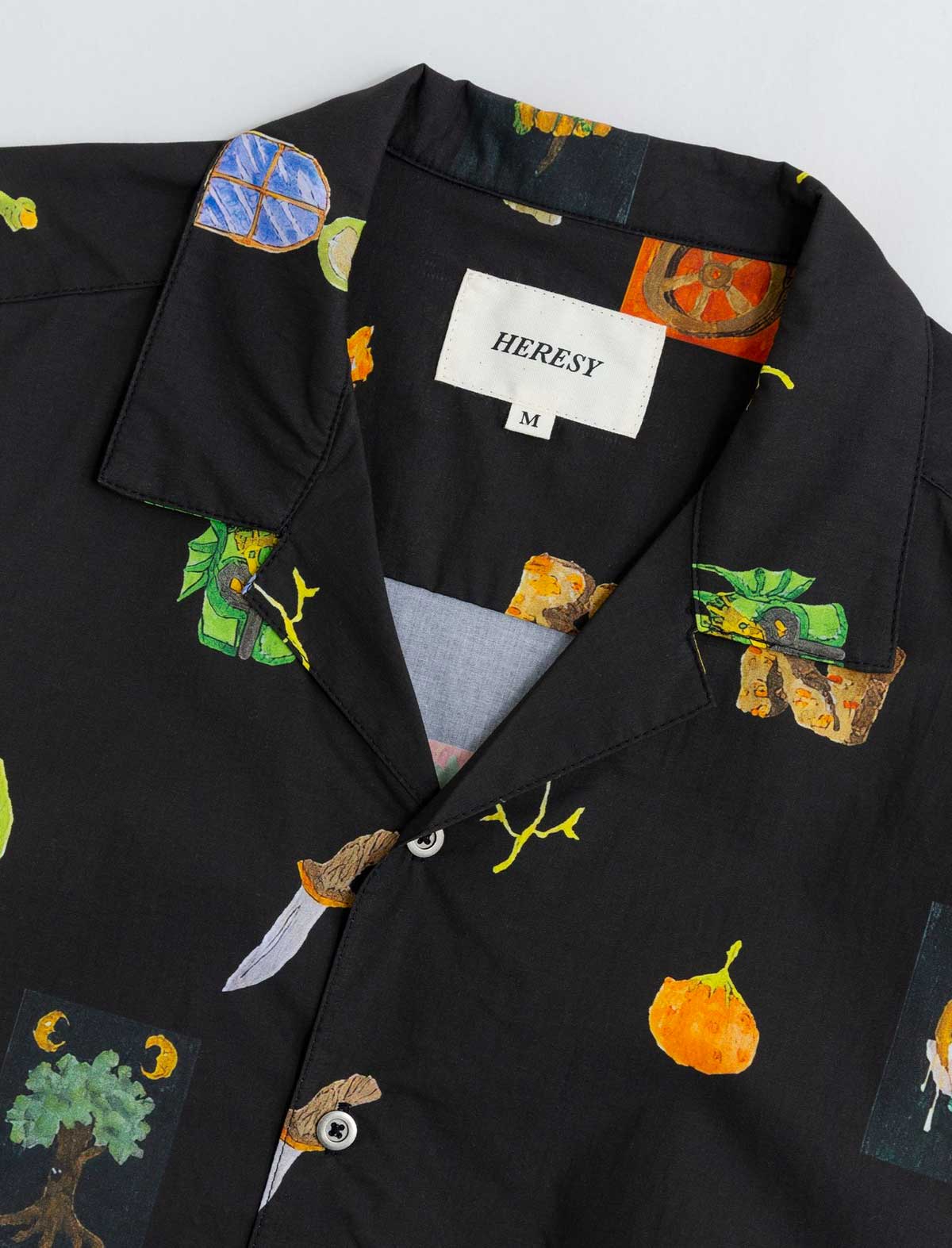 Black shirt with colorful patterns and 'HERESY' label on a white background