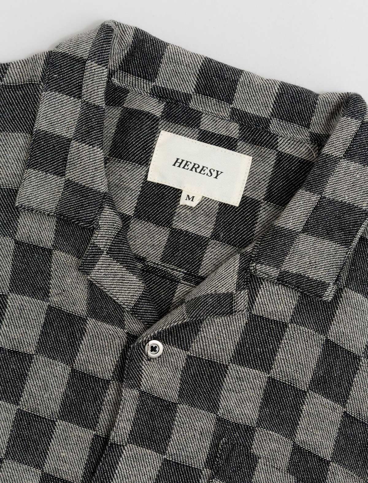Black and gray checkered shirt with 'HERESY' label on a white background