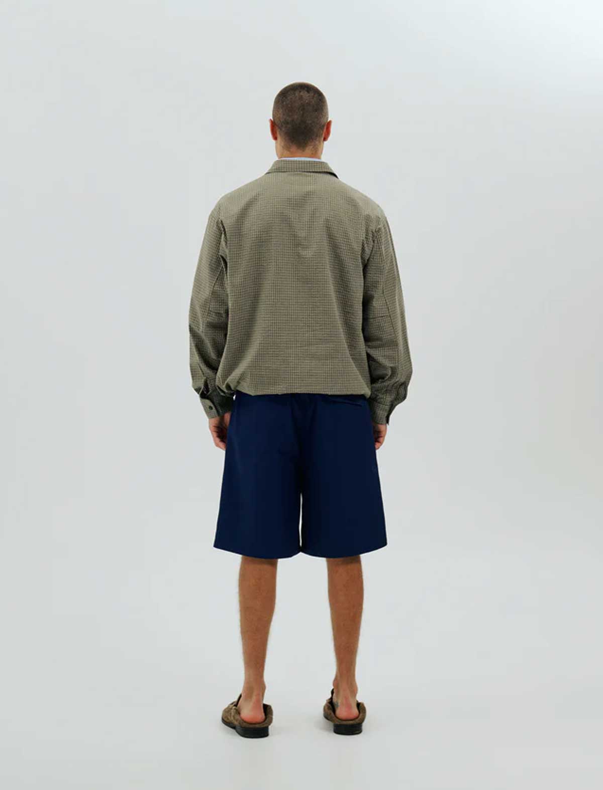 Person wearing a green jacket and blue shorts on a white background