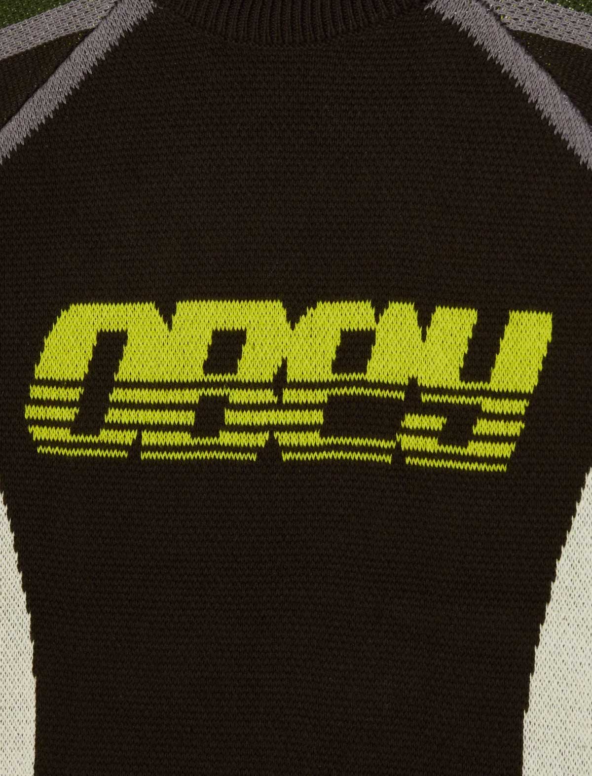Close-up of a black knit garment featuring a large neon yellow-green 'OBEY' logo across the chest, with gray and off-white knit details at the shoulders and sides.