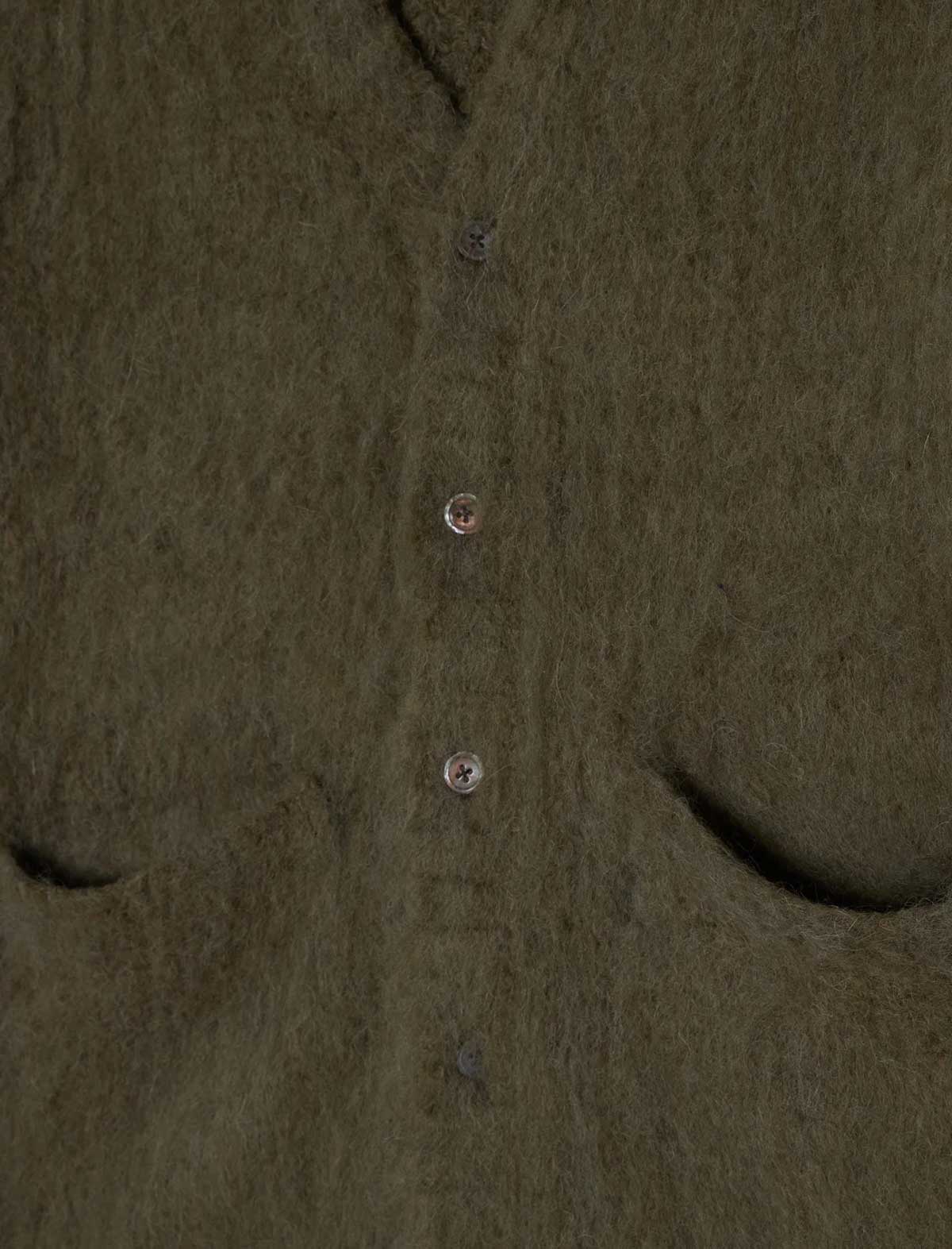Close-up of a fuzzy olive green button-front garment, showing the fabric texture and part of the neckline.