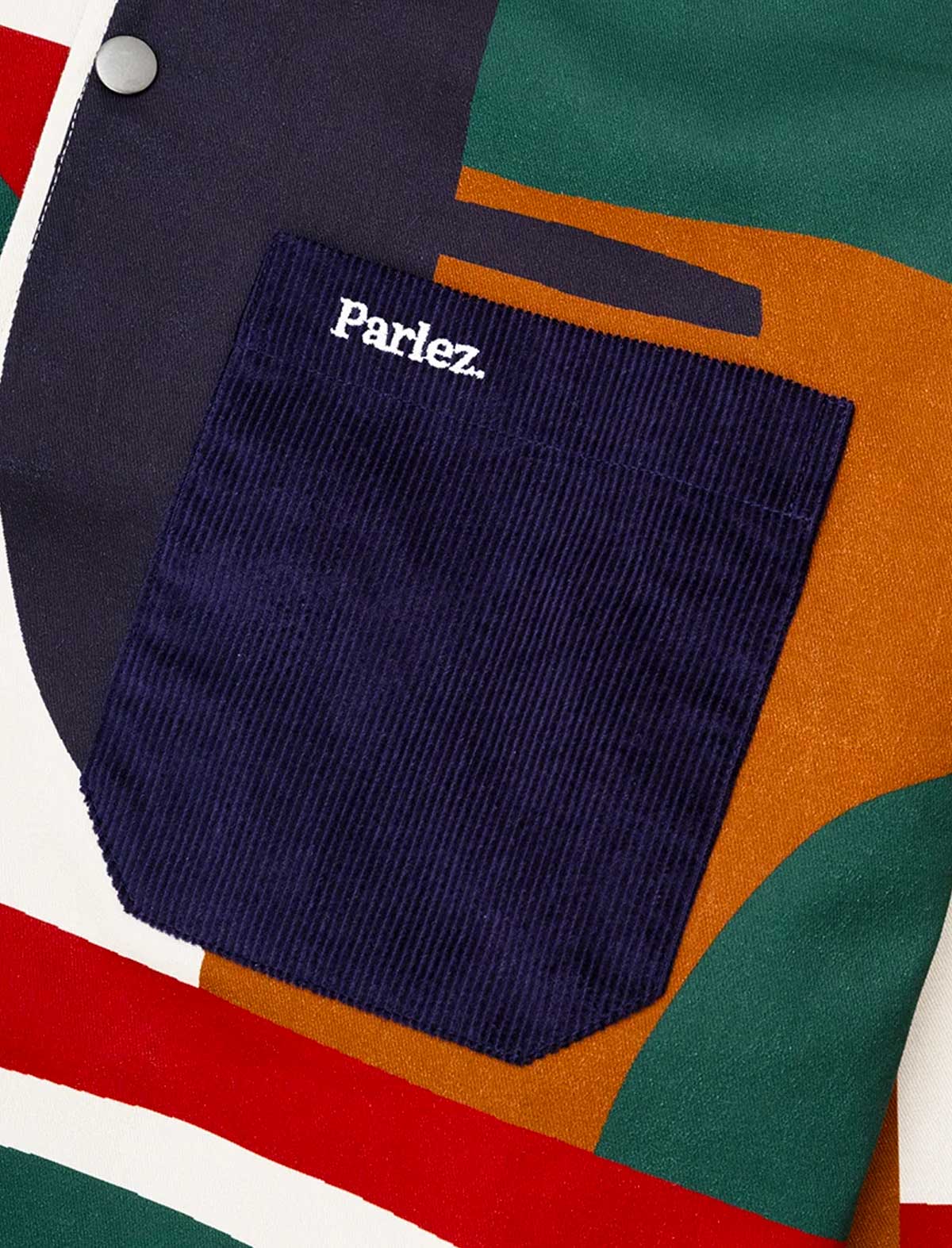 Close-up of the Parlez Bolt Jacket in Multi's navy corduroy chest pocket set against the geometric colour-block print fabric.