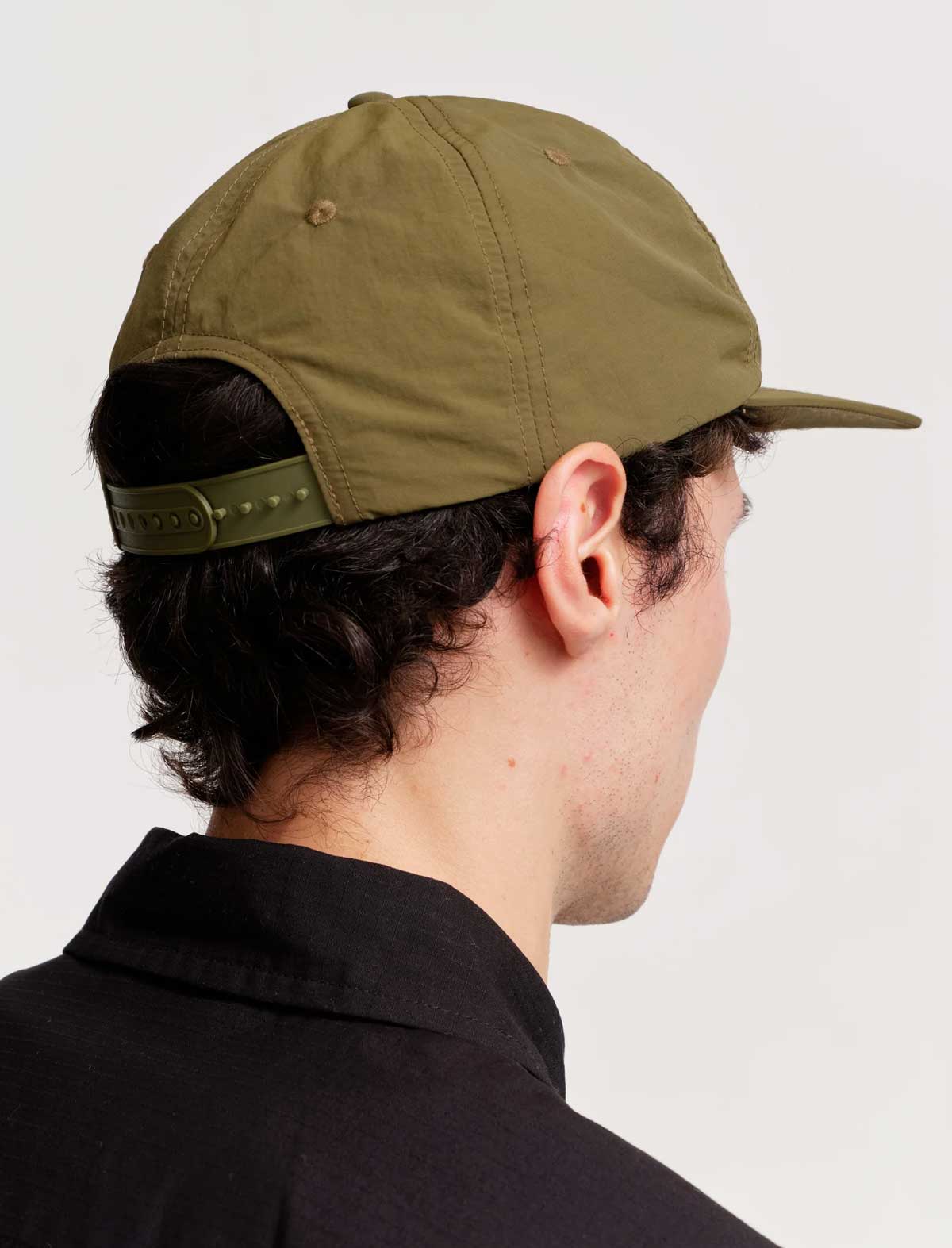 Person wearing a green cap on a plain background