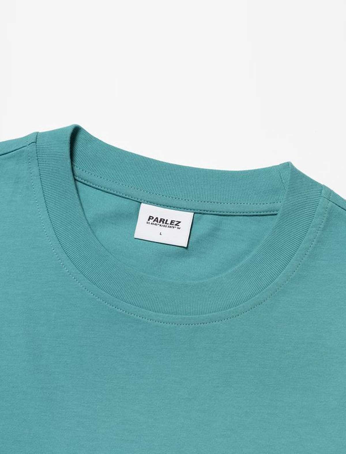Close-up of a parlez complex teal t-shirt with a visible Parlez label on a white background