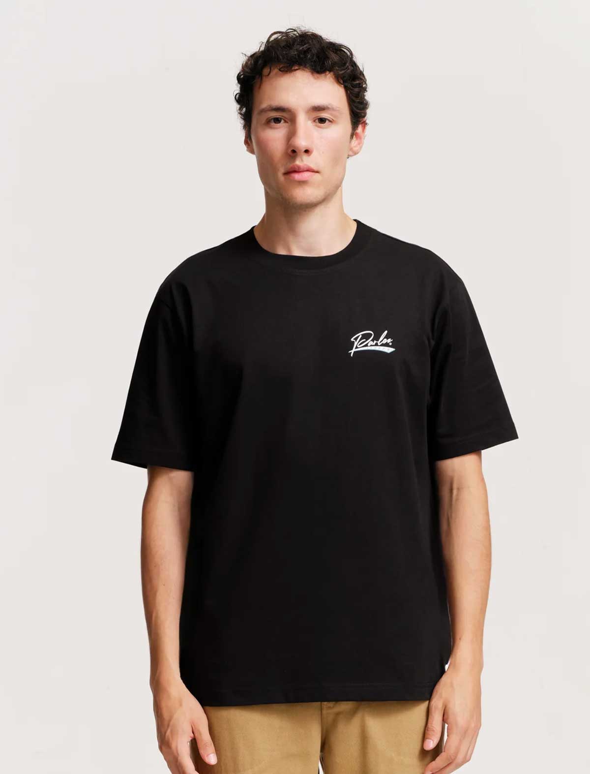 Person wearing a black t-shirt with a logo on a plain background