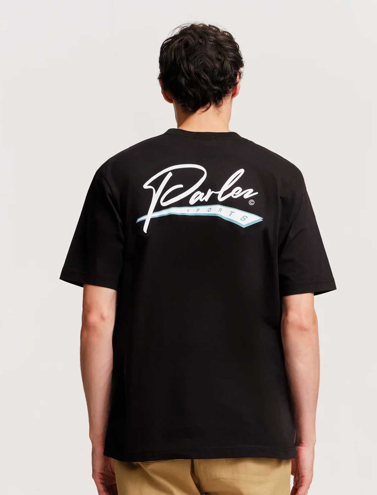 Person wearing a black t-shirt with a logo on the back against a plain background