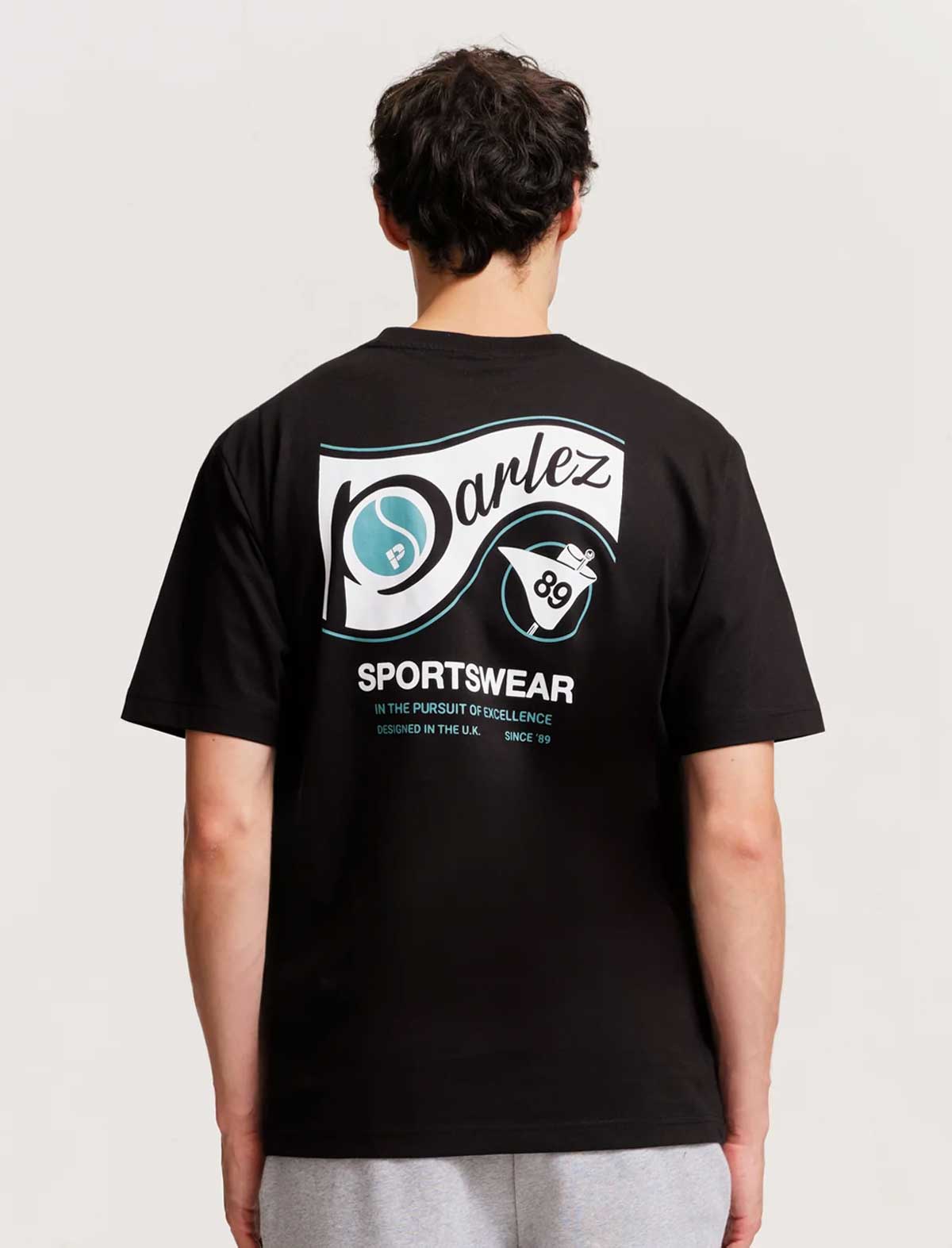 Person wearing a parlez ludis black t-shirt with a brand logo on the back against a plain background