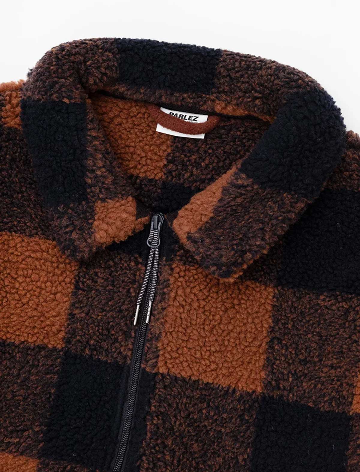 Close-up of a brown and black fleece zip-up jacket with a plaid pattern, featuring a white brand label that reads 'PARLEZ'.