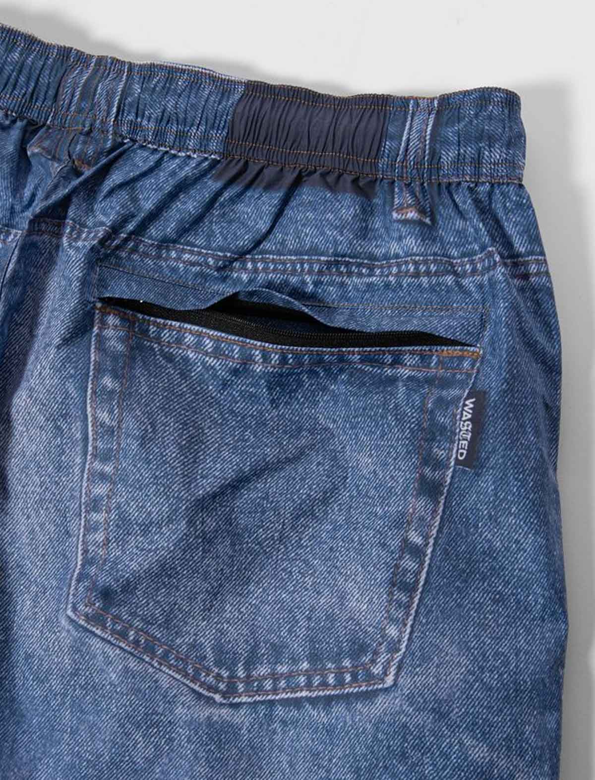 Close-up of Wasted Paris x Umbro Trompe L'Oel Over Pant with a pocket and brand label on a gray background